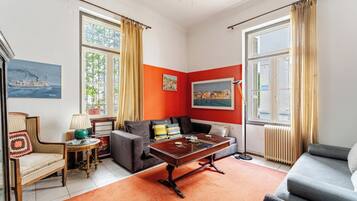 A living room with a sofa, armchair, coffee table, and a painting on the wall.