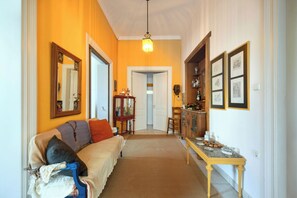 A hallway with a sofa, a table with items, and framed pictures on the wall. - Acropolis Masterpiece Neoclassical  Mansion (Athina)