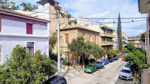 Une rue étroite bordée d’immeubles, de voitures garées et d’arbres.