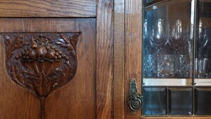 Un meuble en bois doté d’une vitrine où sont exposés des objets en verre.