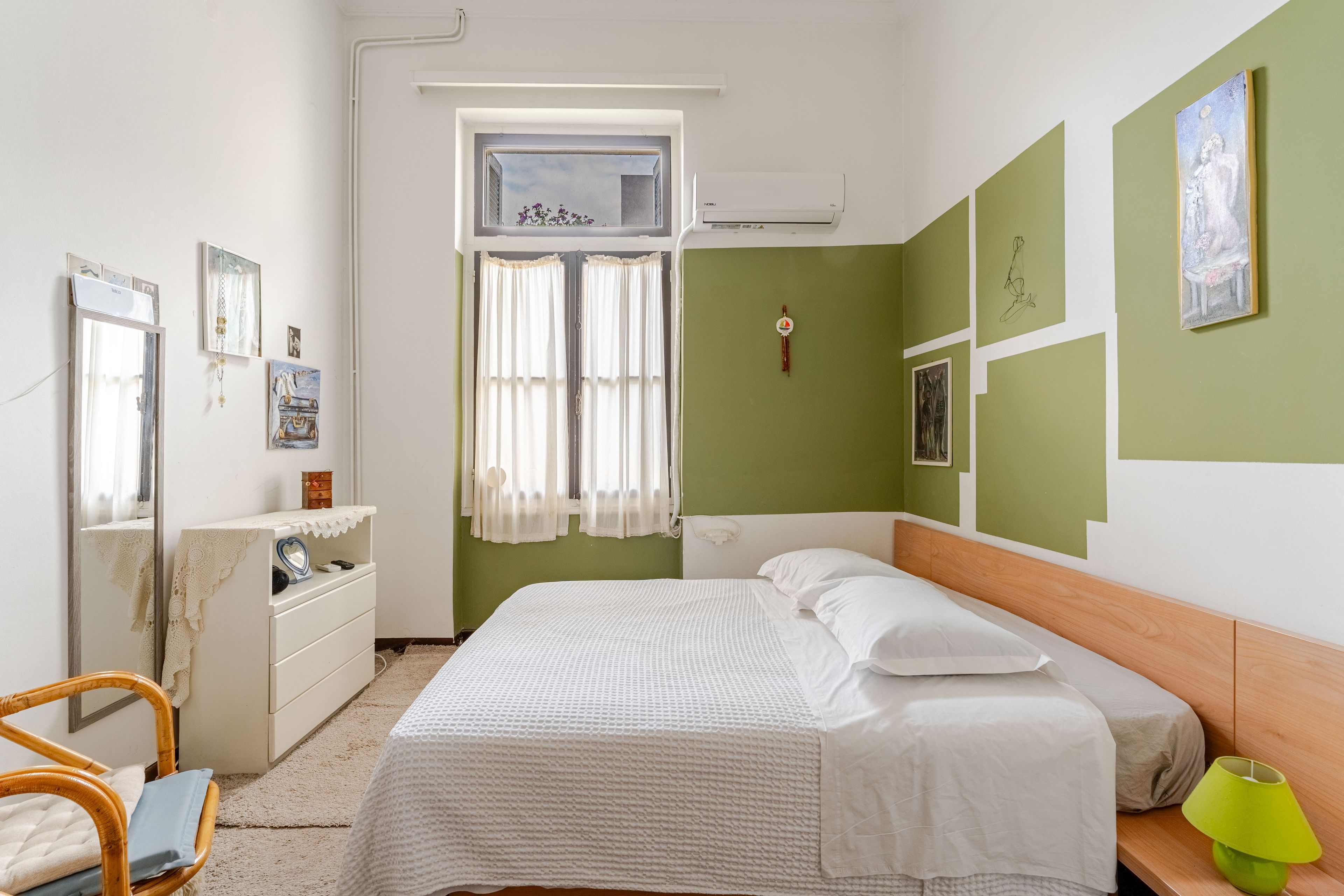 Ein Schlafzimmer mit einem Bett, einem Schminktisch, einem Stuhl und einem fenster mit Vorhängen.