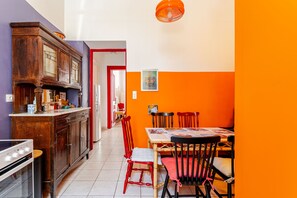 A kitchen with a wooden cabinet, a stove, and a dining area with a table and chairs. - Acropolis Masterpiece Neoclassical Mansion (Athina)
