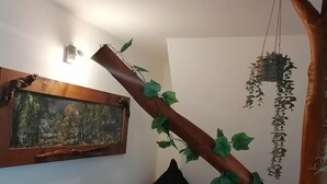 Ein Schlafzimmer mit einem Bett, einer hängenden Pflanze, einem Gemälde und einer Holzk Konstruktion.
