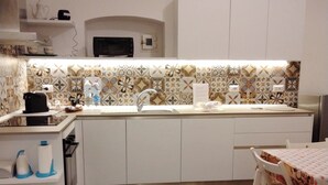 A compact kitchen with a microwave, sink, and white cabinets. A patterned rug and a small dining table with chairs are also visible. - Casa Manzoni, renovated apartment within walking distance of the sea in Bisceglie.   (Bisceglie)