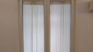 A room with a bed, a wooden floor, and a sliding door with patterned curtains. - Casa Manzoni, renovated apartment within walking distance of the sea in Bisceglie.   (Bisceglie)