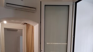 A room with a sliding glass door, wooden flooring, a ceiling-mounted air conditioner, and a visible electrical outlet. - Casa Manzoni, renovated apartment within walking distance of the sea in Bisceglie.   (Bisceglie)