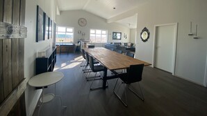 Een ruime keuken met een lange houten tafel, moderne stoelen en uitzicht op het omliggende landschap.