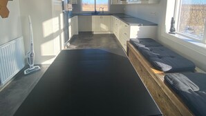 Een moderne keuken met witte kasten, een zwart aanrecht en een groot raam met uitzicht op de omgeving.