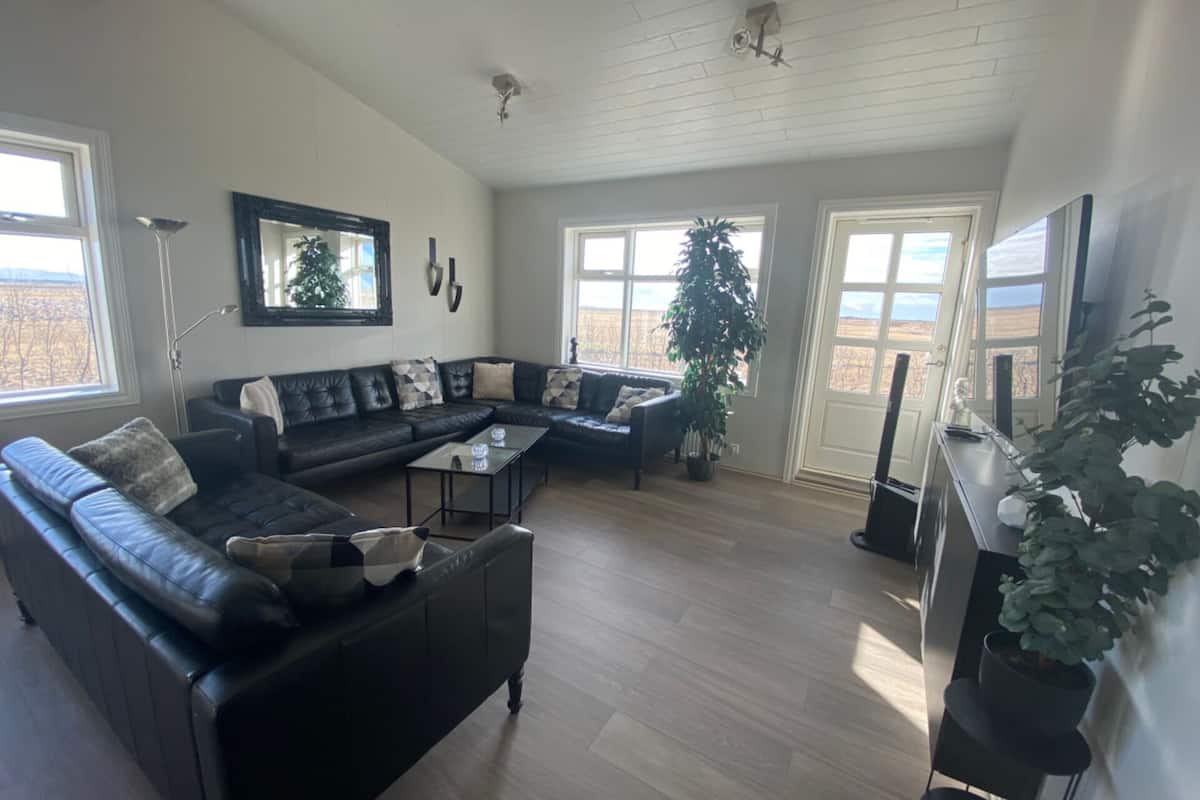 A spacious living room with a sectional sofa, a glass coffee table, and a large window offering a view of the outdoors.