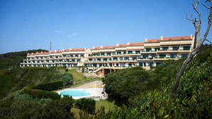 A multi-story hotel with a swimming pool, surrounded by greenery and hills. - Experience Portugal at its finest: Beach, activities,culture -the perfect blend! (Pataias)