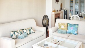 A living room with two sofas, a glass coffee table with seashells, and a decorative vase. - Experience Portugal at its finest: Beach, activities,culture -the perfect blend! (Pataias)