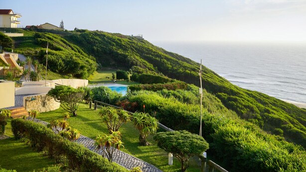 A lush green hillside with a swimming pool and a view of the ocean. - Experience Portugal at its finest: Beach, activities,culture -the perfect blend! (Pataias)