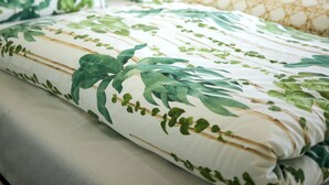 A neatly made bed with floral bedding, a headboard, and a nightstand with a lamp. - Experience Portugal at its finest: Beach, activities,culture -the perfect blend! (Pataias)