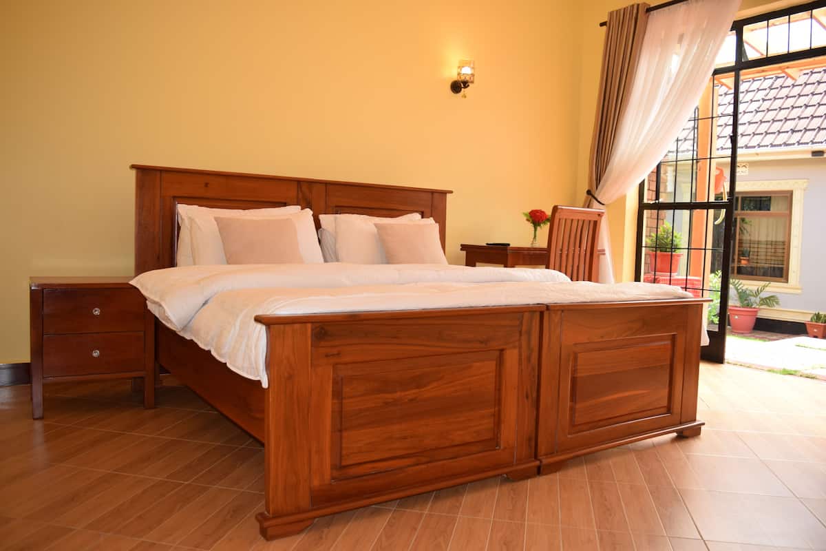 Una cama de madera con cabecera, una mesita de noche y una lámpara fijada a la pared.