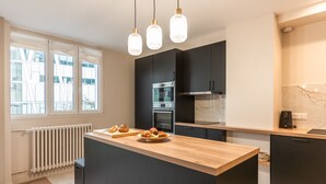 Une cuisine moderne dotée d’un îlot central, de meubles noirs et d’un radiateur blanc.