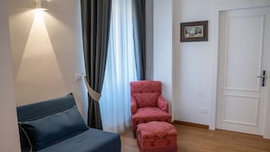 Ein Zimmer mit einem blauen Sofa, einem roten Sessel und Holzboden.