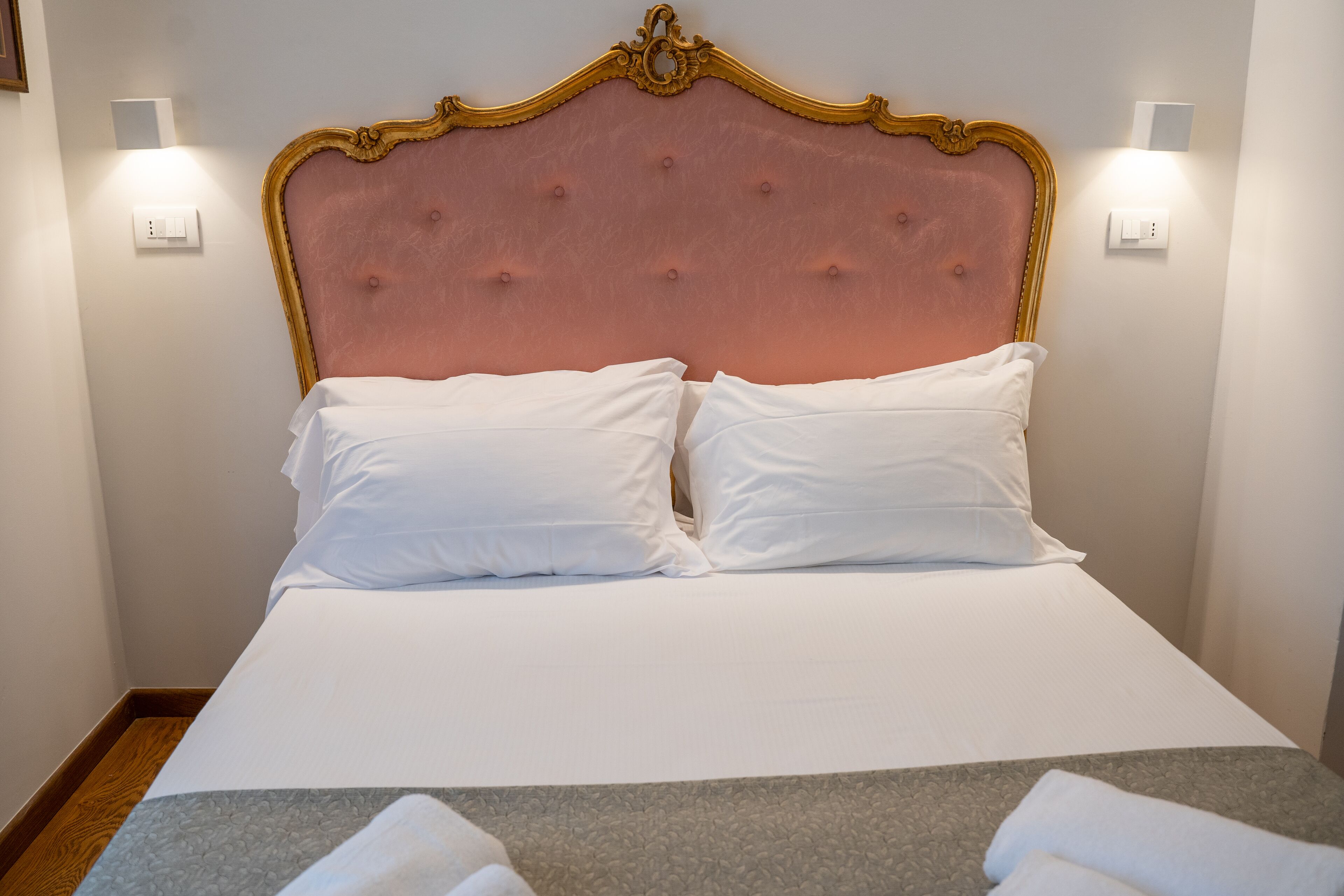 A neatly made bed with a pink headboard and white bedding.