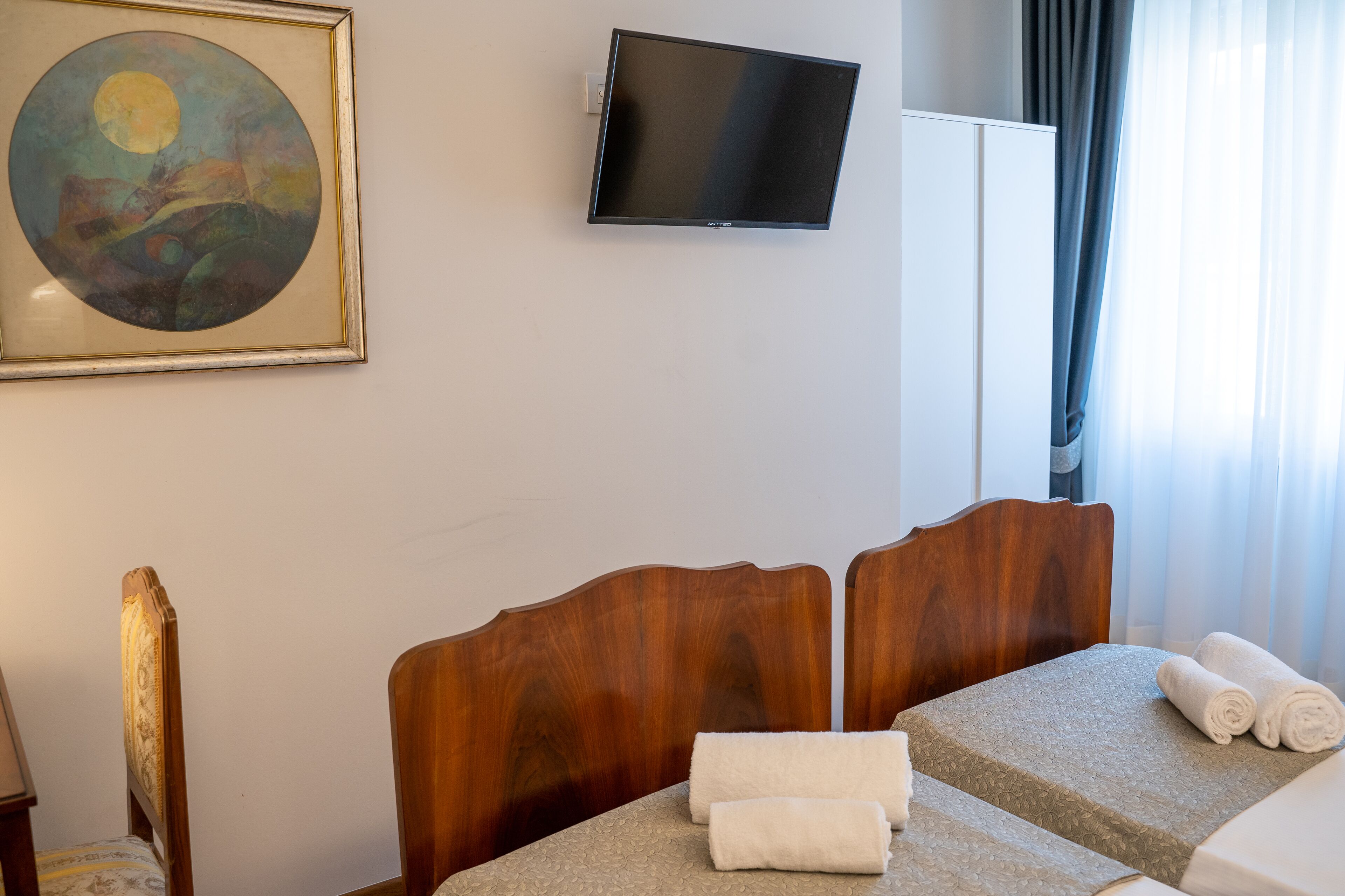 A hotel room with a bed, a television, and a painting on the wall.