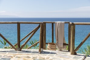 Una terraza de madera con vistas al mar, una cesta tejida y un paño color beige.