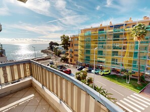 Un balcone con vista su una strada costiera, un edificio in costruzione e un cielo sereno.