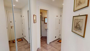 A hallway with mirrored walls, a door with a handle, and two framed pictures on the wall. - Cozy 3P with air conditioning and balcony, near beaches (Menton)