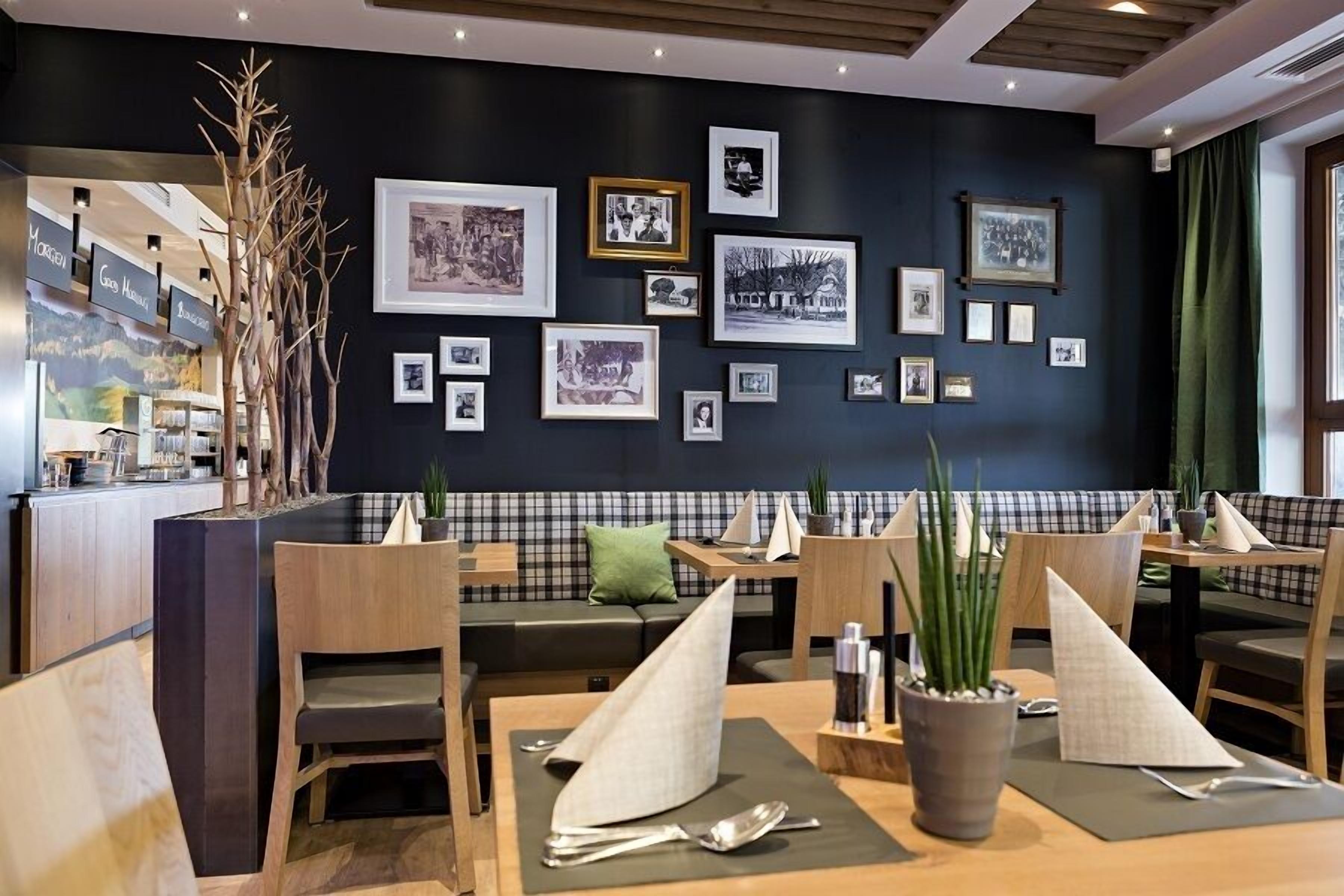 A restaurant with a black wall adorned with framed photographs, wooden furniture, and a checkered bench area.