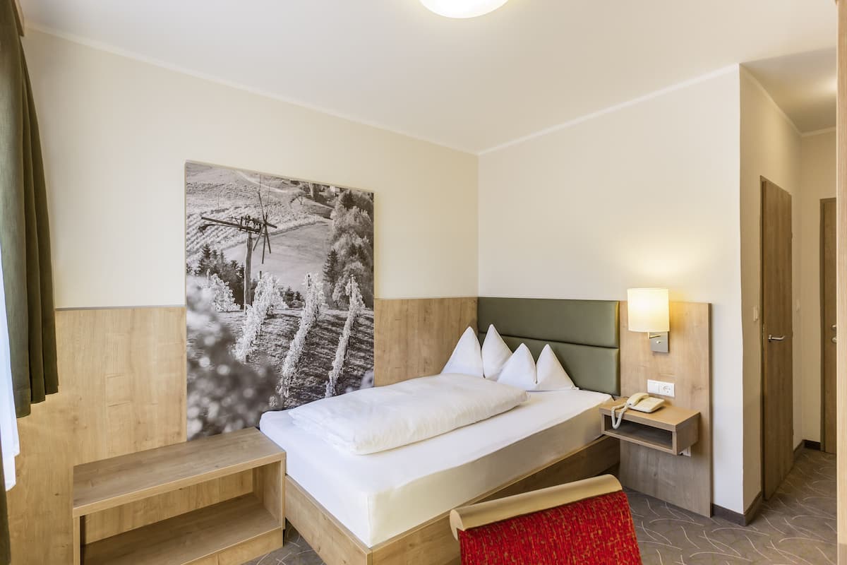 Une chambre d’hôtel avec un lit, une table de chevet avec une lampe, un téléphone et un grand tableau en noir et blanc accroché au mur.