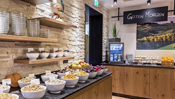 Zona de buffet con diversas opciones de comida y un letrero que dice 'Guten Morgen'.