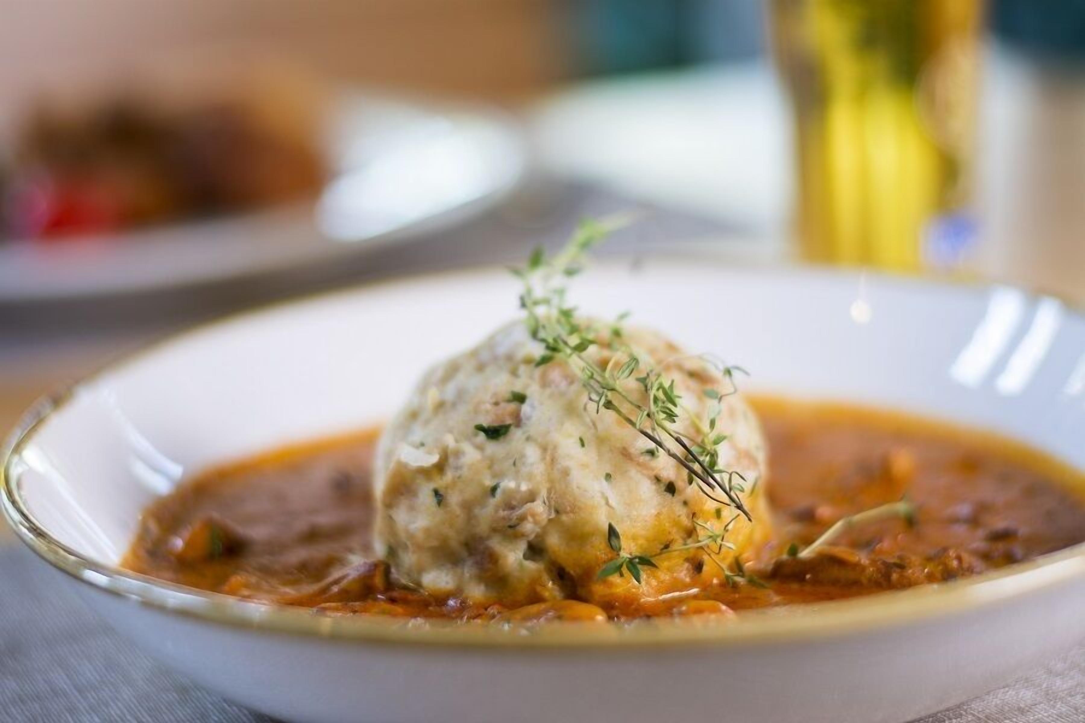 A dish with a dumpling in a sauce, garnished with herbs.