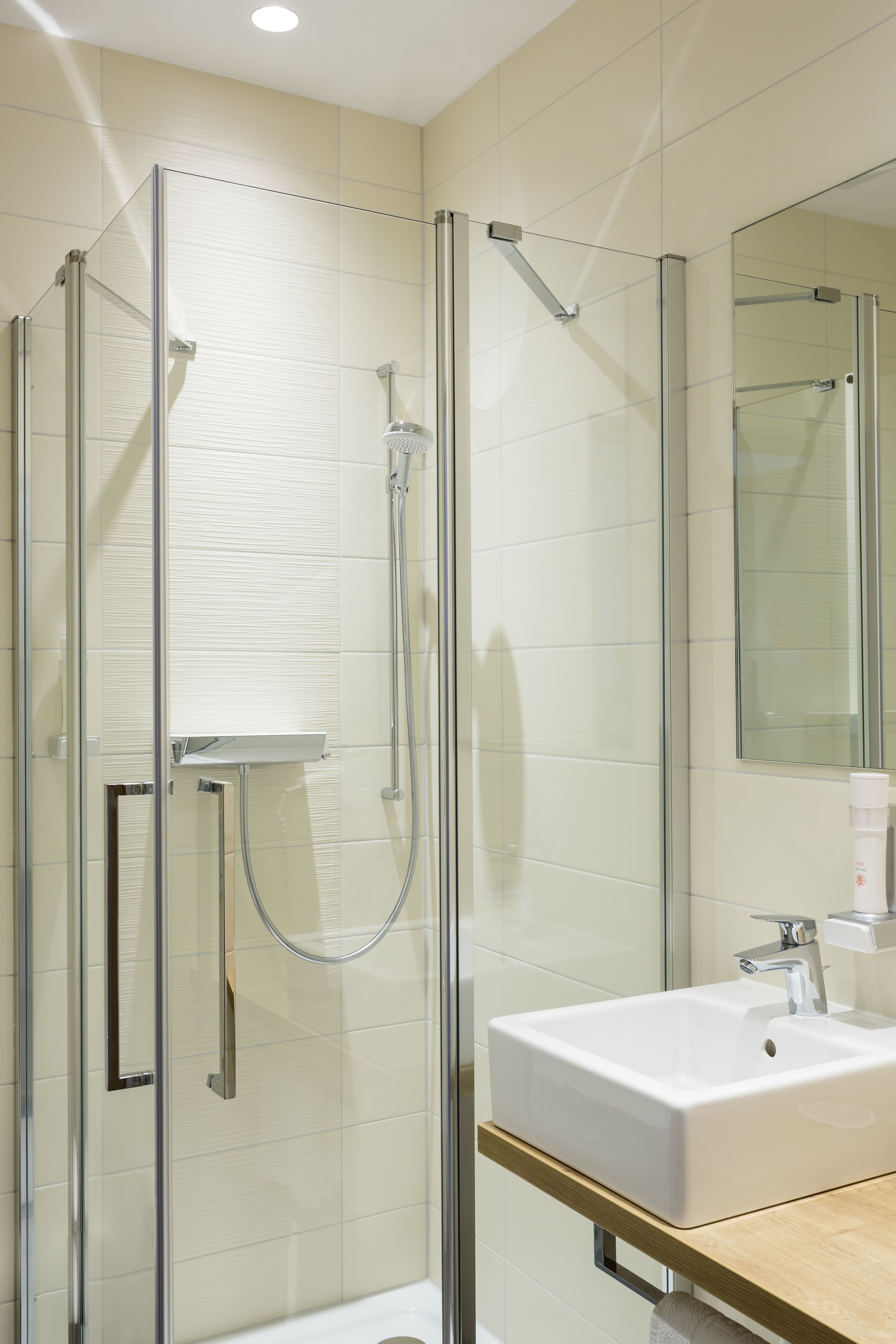 A modern bathroom with a glass-enclosed shower, a white sink, and a mirror above the sink.