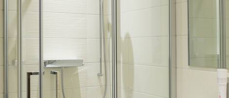 A modern bathroom with a glass-enclosed shower, a white sink, and a mirror above the sink.