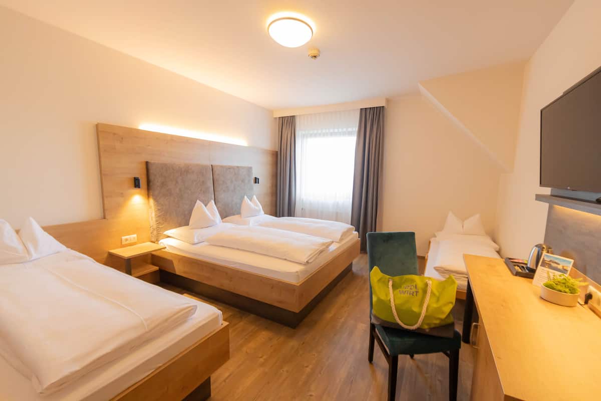 Une chambre d’hôtel avec deux lits simples, un bureau avec une chaise, une télévision et une fenêtre avec des rideaux.