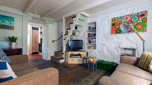 Un salon comprenant un canapé, un téléviseur, une bibliothèque et un tableau abstrait aux couleurs vives accroché au mur.
