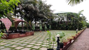 Un patio empedrado con plantas en macetas, un muro de ladrillo y un edificio al fondo.