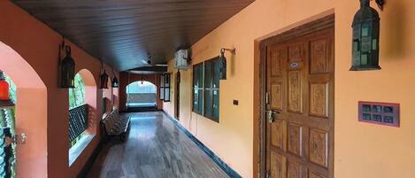A corridor with a wooden ceiling, a wooden door with intricate carvings, and a bench along the wall.