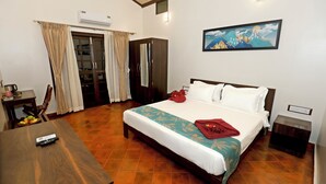 Habitación de hotel con cama, escritorio, silla, armario y un cuadro en la pared.