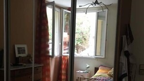 Un dormitorio con cama, escritorio, silla, armario y ventana.