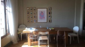 Un comedor con una mesa de madera, sillas traslúcidas y cuadros en la pared.
