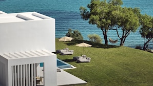 A modern building with a pool, outdoor seating, and a view of the sea. - Omnia Villa (Zakynthos)