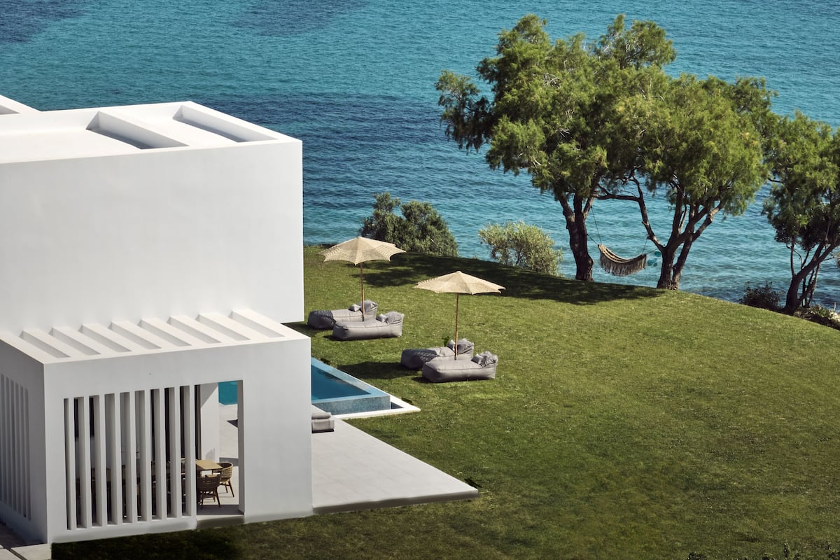 A modern building with a pool, outdoor seating, and a view of the sea.