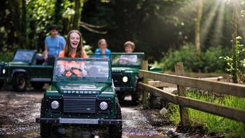 A green Defender vehicle driving through a muddy path with passengers.
