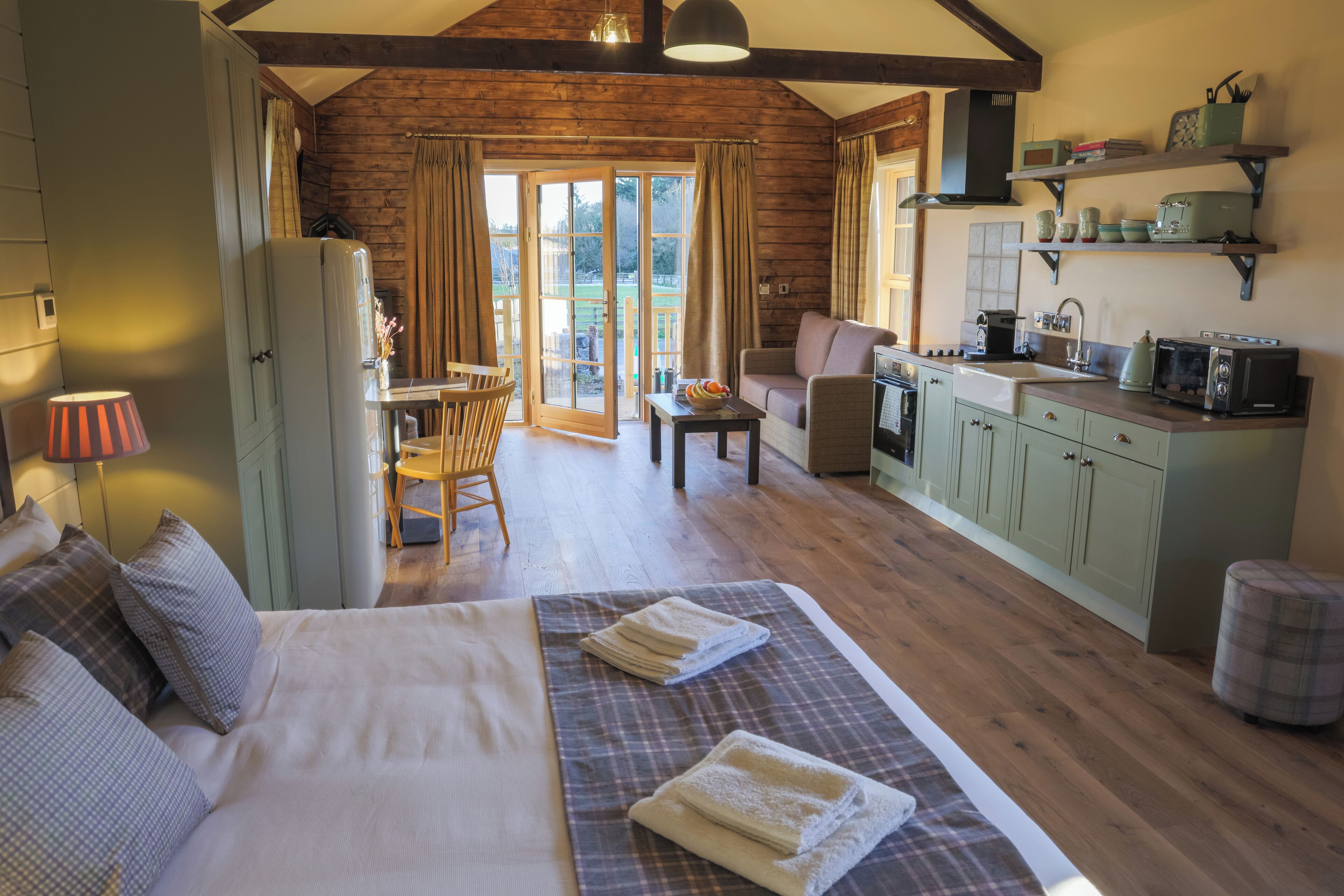 A cozy room with a bed, a dining table, and a kitchenette.