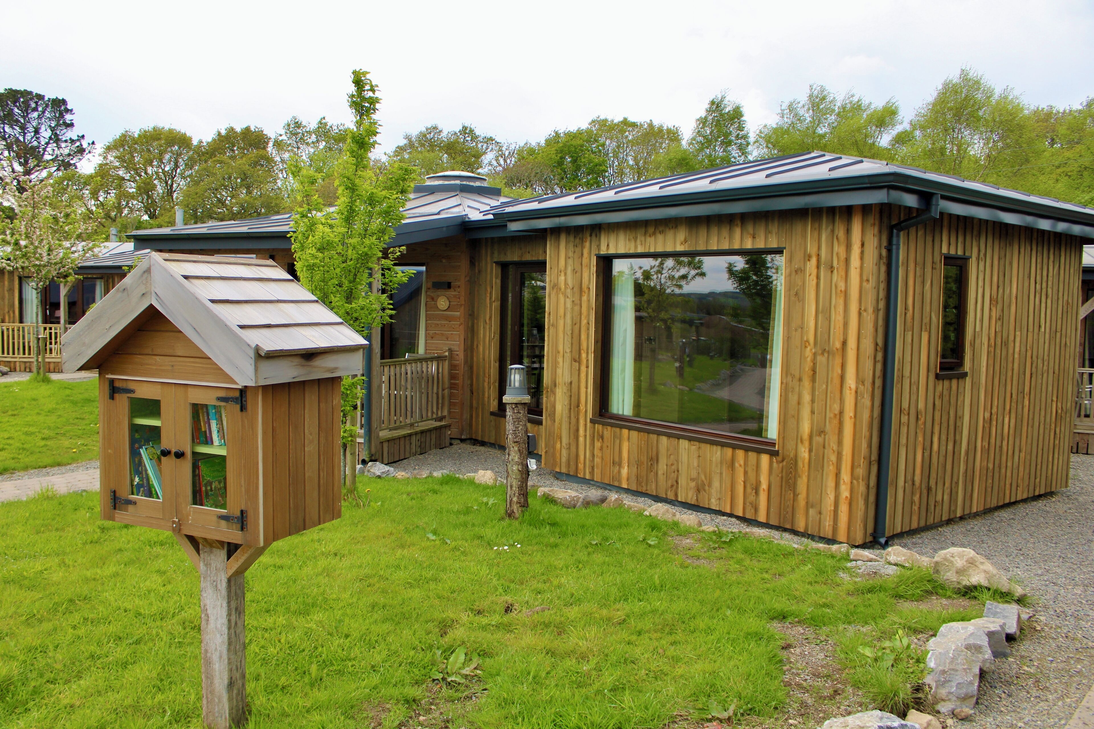 A wooden cabin with a large window and a small attached structure with a slanted roof.