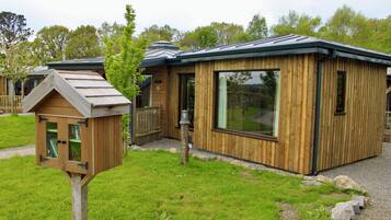 A wooden cabin with a large window and a small attached structure with a slanted roof.