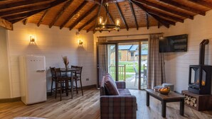 A cozy room with a wooden ceiling, a sofa, a table with fruit, a TV, and a fireplace.