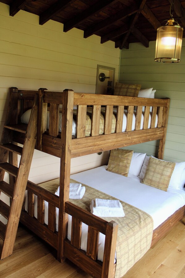 A bunk bed with a wooden ladder, a white mattress, and plaid bedding. - Wildlands (Ballycuirke East)
