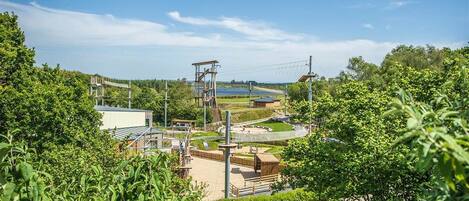 A view of a park with a playground, a small building, and a body of water in the background.