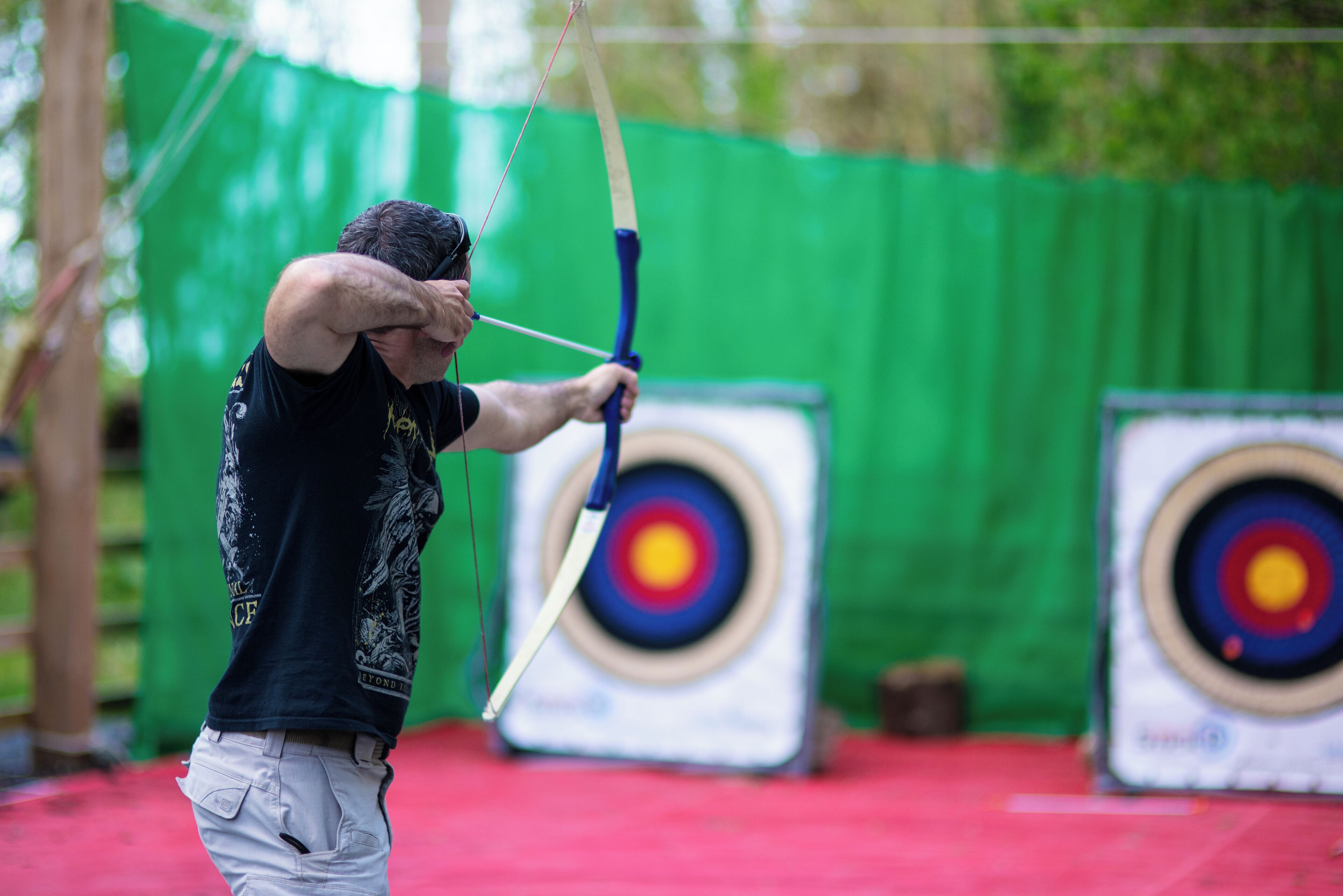 An indoor archery range with targets and a person aiming a bow.