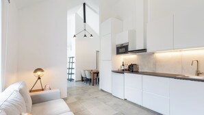 Una cocina moderna con armarios blancos, microondas integrado y un lavamanos de acero inoxidable.