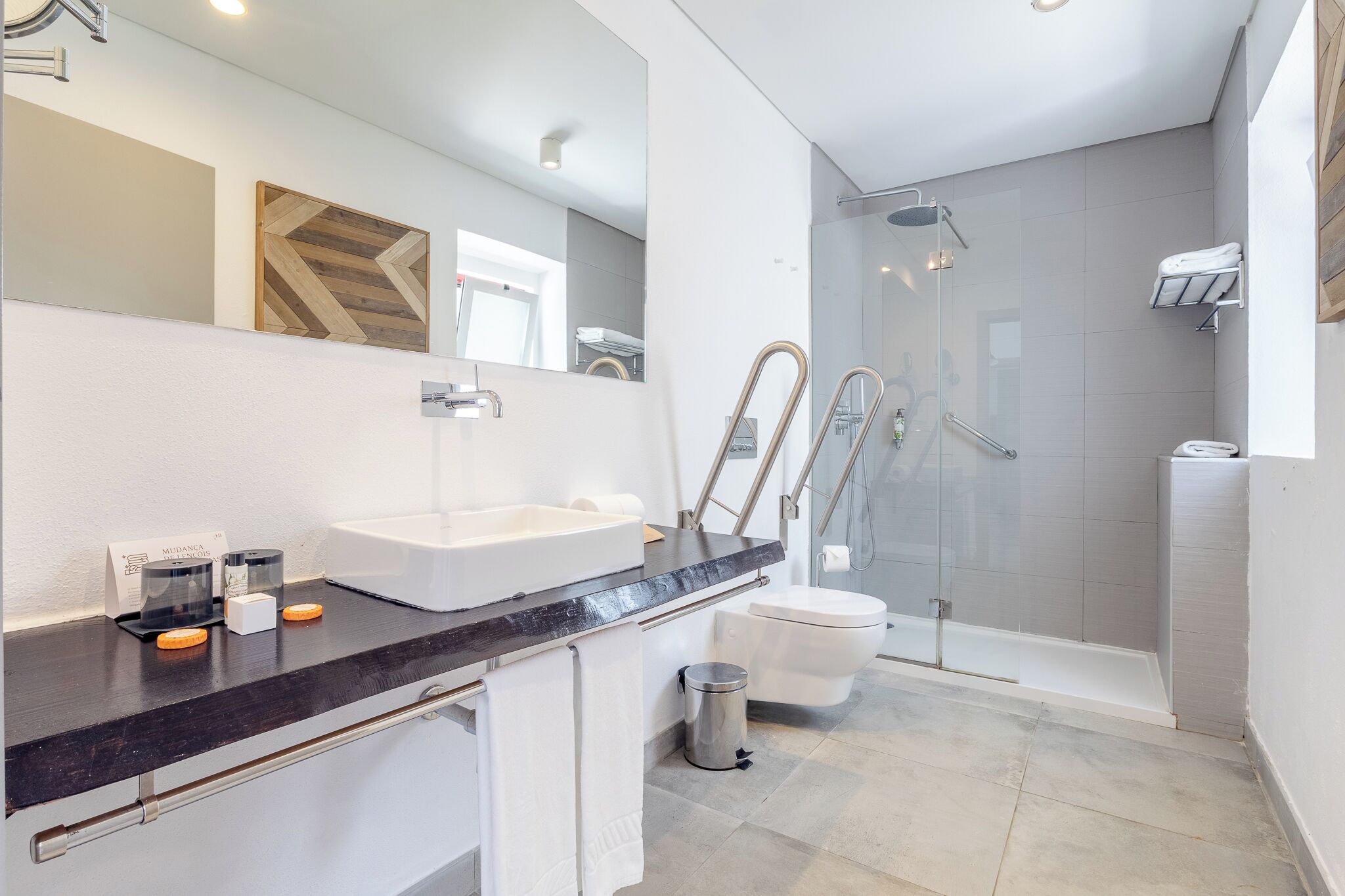 A modern bathroom with a black countertop, two sinks, a toilet, and a glass-enclosed shower.